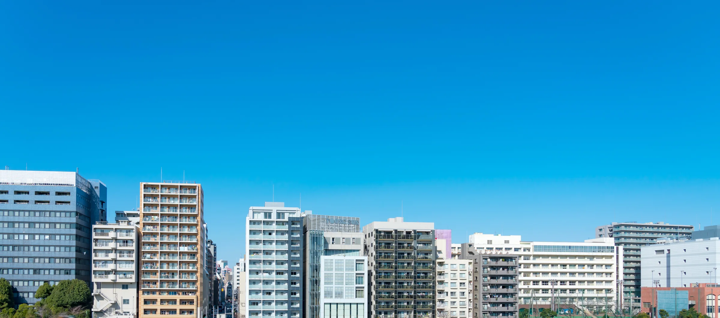 青空の下に建ち並ぶ都市部のマンション