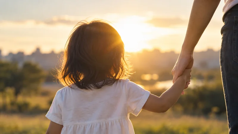 夕暮れのなか、手をつないで歩く子どもと大人